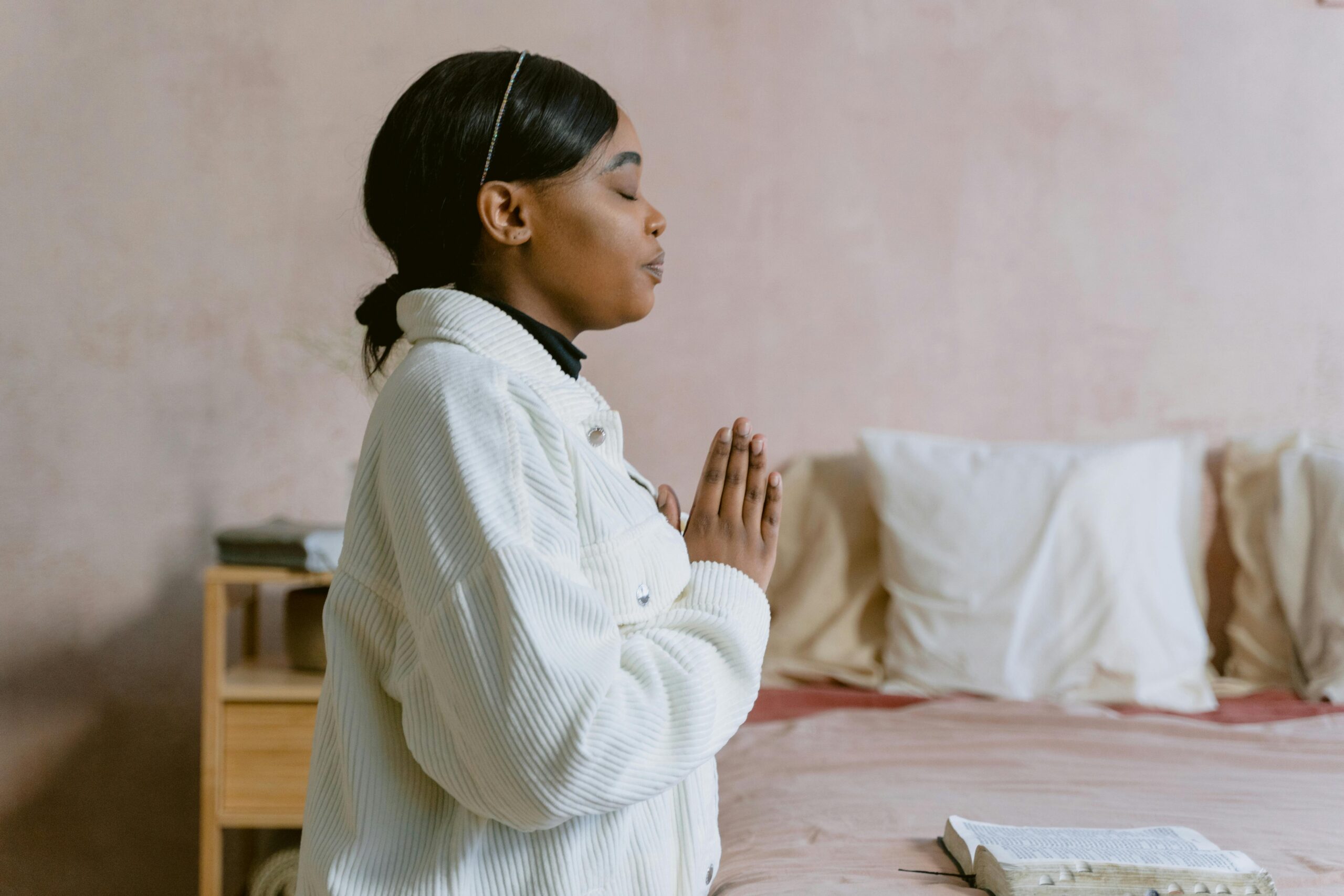 A serene image of a woman with closed eyes in prayer, capturing a moment of spiritual reflection indoors.